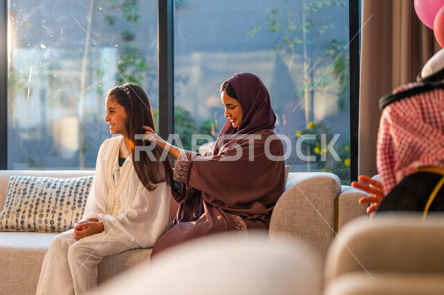 1Taking care of the external appearance, a Saudi Arabian Gulf mother styling her daughter’s hair, wearing traditional costumes on holidays and religious occasions, joy and happiness for the arrival of Eid.