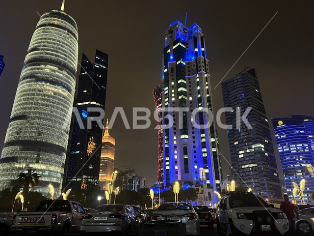 Residential and commercial towers and facilities on the Doha Corniche at night, the economic and urban renaissance of the city of Doha, advanced architectural engineering art, famous tourist attractions and places in Qatar, continuing and competing in the development and modernization of engineering designs for buildings and towers.