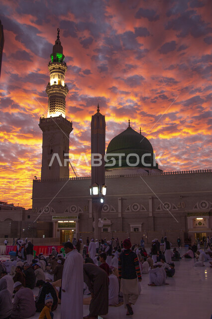 تجمع المسلمون في الساحة الخارجية للحرم النبوي الشريف في المدينة المنورة، معالم دينية مقدسة في المملكة العربية السعودية، اسلاميات وعبادة، منظر السماء المليئة بالغيوم والسحب وقت غروب الشمس، الطاعة والتقرب إلى الله, الفن الهندسي المعماري الاسلامي لمسجد رسول الله