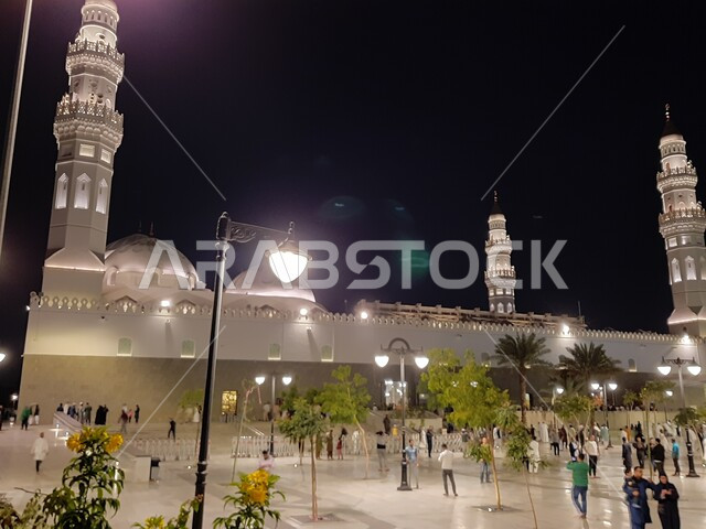 تجمع المصلين والزائرين في الفناء الخارجي للجامع، الفن الهندسي المعماري المتميز والديكورات الاسلامية على الطراز الحديث، العبادة والتقرب إلى الله، مآذن و قبب مسجد قباء المضيئة في المدينة المنورة ليلا، معالم و أماكن دينية مقدسة في المملكة العربية السعودية