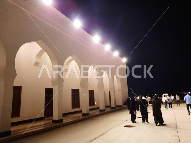 الزوار والمصلين في الفناء الخارجي للجامع، قبب ومآذن مسجد العريش المضيئة في بدر قرب المدينة المنورة ليلا، الفن الهندسي المعماري المتميز والديكورات الاسلامية على الطراز الحديث، العبادة والتقرب إلى الله، معالم و أماكن دينية مقدسة في المملكة العربية السعودية