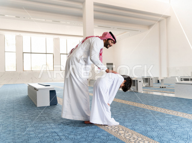 تعليم أداء فريضة الصلاه للطفل داخل المسجد، رجل سعودي يصلي في المصلى بجانب ابنه البالغ ،الخشوع في الصلاه ، أداء فريضة الصلاه في المسجد ، العبادة و التقرب الى الله ، تعليم الصلاة للأطفال