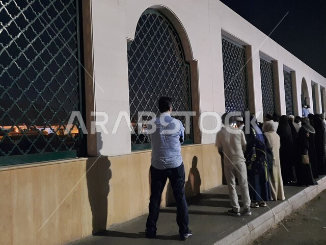 المناطق التراثية الشعبية الأثرية التاريخية، مقر شهداء غزوة بدر في المدينة المنورة في وضع الليل، تجمع الزوار امام النوافذ الحديدية المطلة على المقبرة، أماكن ومعالم إسلامية دينية مشهورة في المملكة العربية السعودية 