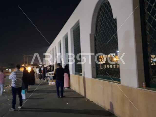 المناطق التراثية الشعبية الأثرية التاريخية، مقر شهداء غزوة بدر في المدينة المنورة في وضع الليل، تجمع الزوار امام النوافذ الحديدية المطلة على المقبرة، أماكن ومعالم إسلامية دينية مشهورة في المملكة العربية السعودية 