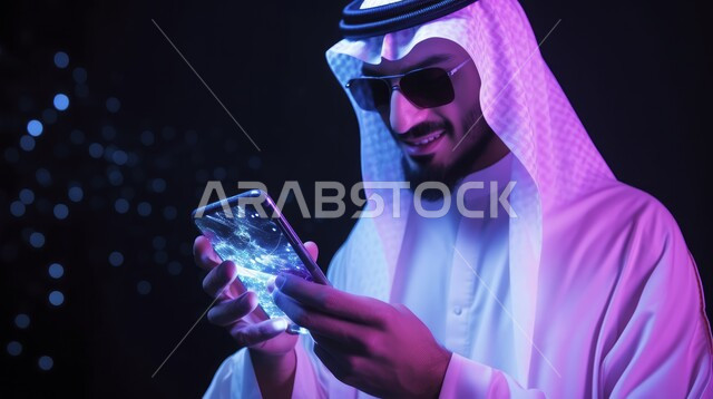 تصفح الانترنت ومواقع التواصل الاجتماعي، استخدام التكنولوجيا الحديثة والمتطورة، التحدث والدردشة مع الأهل والأصدقاء عبر الانترنت, صورة مقربة لرجل عربي خليجي سعودي يرتدي الزي التقليدي يحمل بيده الهاتف الجوال، التطورات التقنية والتكنولوجيا الرقمية