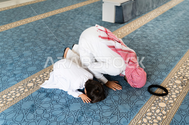 تعليم أداء فريضة الصلاه للطفل داخل المسجد، رجل سعودي يصلي في المصلى بجانب ابنه البالغ ،الخشوع في الصلاه ، أداء فريضة الصلاه في المسجد ، العبادة و التقرب الى الله ، تعليم الصلاة للأطفال
