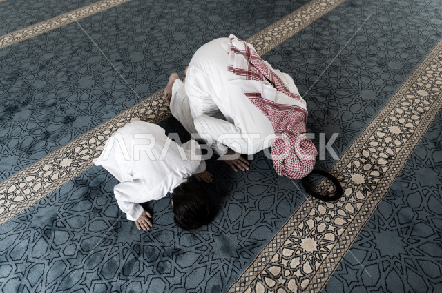 تعليم أداء فريضة الصلاه للطفل داخل المسجد، رجل سعودي يصلي في المصلى بجانب ابنه البالغ ،الخشوع في الصلاه ، أداء فريضة الصلاه في المسجد ، العبادة و التقرب الى الله ، تعليم الصلاة للأطفال