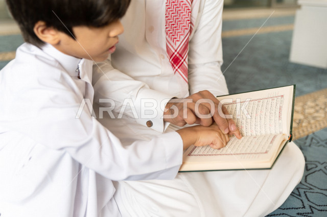 رجل سعودي مسلم يجلس داخل المسجد و بجانبه طفل صغير ، يقرآن القرآن الكريم ، تحفيظ القرأن الكريم  للأطفال ، تلاوة القرآن الكريم ، العبادة و التقرب الى الله