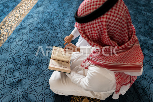 رجل سعودي مسلم يجلس داخل المسجد و بجانبه طفل صغير ، يقرآن القرآن الكريم ، تحفيظ القرأن الكريم  للأطفال ، تلاوة القرآن الكريم ، العبادة و التقرب الى الله