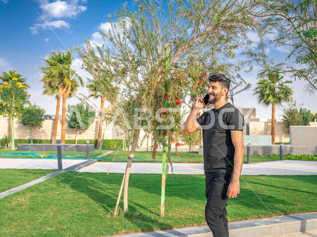 المنتزهات والحدائق العامة، الدردشة والتواصل مع الأهل والاصدقاء، رجل عربي خليجي سعودي مبتسم، نشاط بدني في الهواء الطلق، اجراء مكالمات الهاتفية اثناء ممارسة التمارين الرياضيه، الحفاظ على الرشاقه والنشاط البدني، تبادل الاحاديث المضحكة والمسلية عبرالموبايل