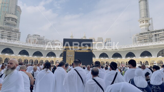 أداء مناسك الحج والعمرة، العبادة والتقرب الى الله، قبلة الاسلام والمسلمين، صورة من الخلف لمجموعة من المعتمرين يرتدون ملابس الإحرام في بيت الله الحرام في الحرم المكي الشريف في السعودية، أماكن ومعالم إسلامية مقدسة، طواف الحجاج حول الكعبة المشرفة في مكة المكرمة