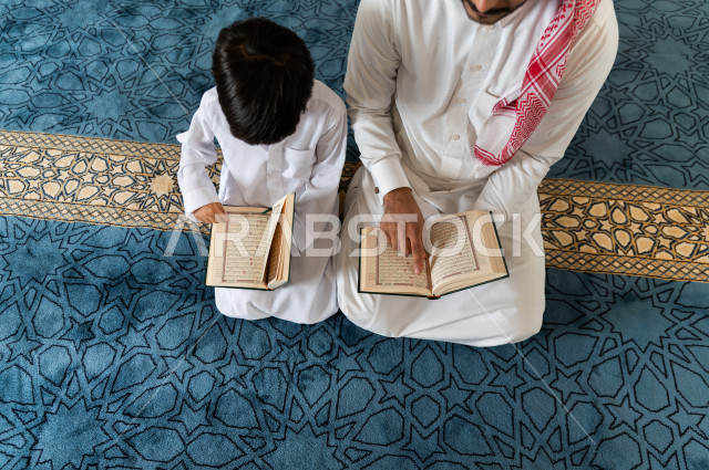 رجل سعودي مسلم يجلس داخل المسجد و بجانبه طفل صغير ، يقرآن القرآن الكريم ، تحفيظ القرأن الكريم  للأطفال ، تلاوة القرآن الكريم ، العبادة و التقرب الى الله