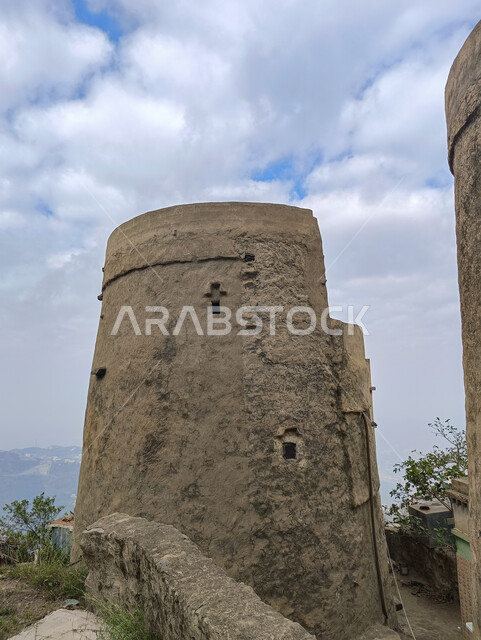 Historical archaeological monuments on the slopes of the mountains in the city of Jazan, a close-up of an ancient castle on agricultural terraces in Saudi Arabia, residential buildings and houses on the mountain peaks and heights in Faifa Governorate, trees and green plants, nature background