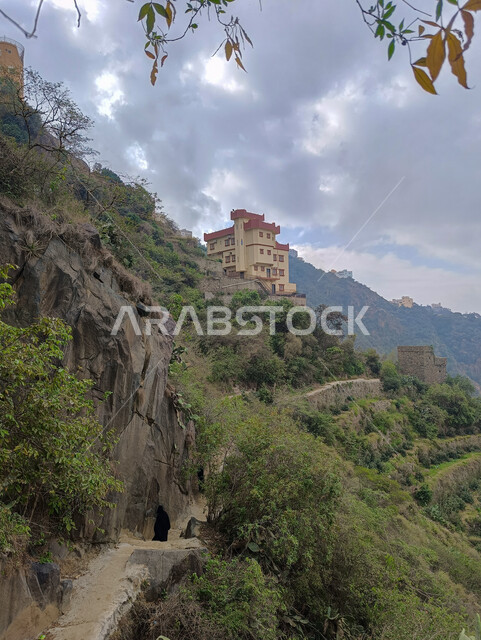 منظر السماء المليئة بالغيوم البيضاء فوق سفوح الجبال، النباتات الخضراء والأشجار، المعالم الاثرية التاريخية على القمم والمرتفعات الجبلية في مدينة جازان، المباني القديمة في محافظة فيفاء في المملكة العربية السعودية، خلفية الطبيعة