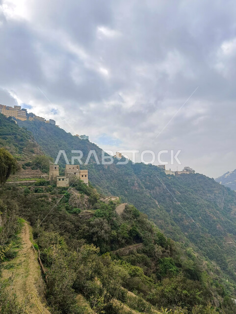 السماء المليئة بالغيوم البيضاء فوق سفوح الجبال، الأشجار والنباتات الخضراء، المعالم الاثرية التاريخية على القمم والمرتفعات الجبلية في مدينة جازان، المباني القديمة في محافظة فيفاء في المملكة العربية السعودية، خلفية الطبيعة