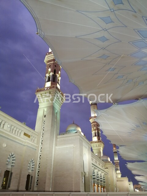 Electronic umbrellas in Al-Haram Square in Medina at sunset, worship and closeness to God, holy Islamic religious places in the Kingdom of Arabia, the destination of Muslims to perform worship and religious duties, the architectural engineering art of building mosques in Saudi Arabia, minarets and domes of the Prophet’s Mosque