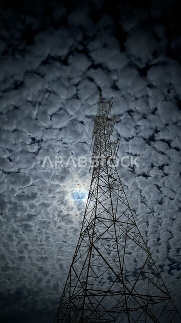 منظر القمر المختبئ خلف الغيوم والحسب البيضاء في السماء وقت الليل، صورة مقربة لبرج نقل كهربائي عالي الجهد, محطات توزيع الكهرباء في المملكة العربية السعودية،  اعمدة وابراج الطاقة الكهربائية 