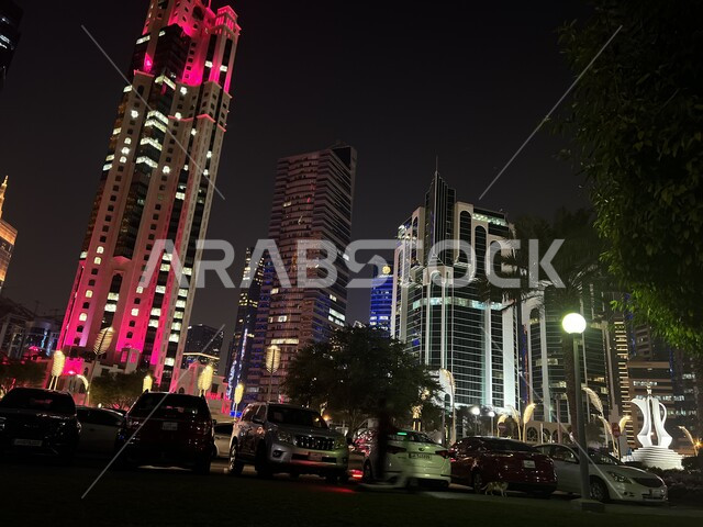 Famous landmarks and places in the State of Qatar, interest in planting trees and green plants in tourist cities, residential and commercial towers and facilities illuminated at night on the Doha Corniche, the economic and urban renaissance of the city of Doha, advanced architectural engineering art.