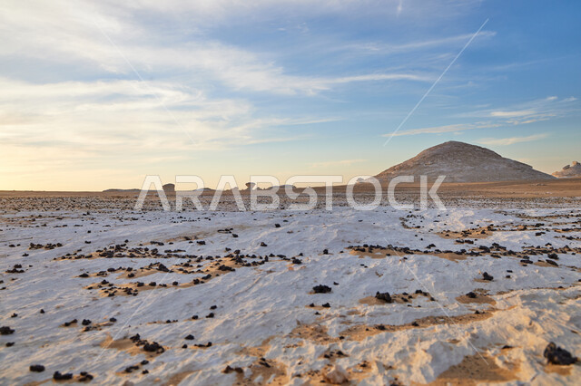 The fusion of white and golden sand, ancient historical monuments, natural mountain peaks and heights in the sandy environment, famous tourist places, rock formations and formations in the Saudi desert, a view of the sky full of white clouds, attracting and attracting tourists.