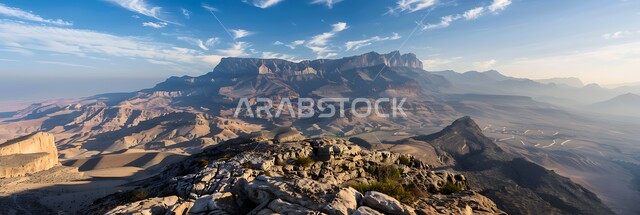  منظر الغيوم والسحب البيضاء في السماء فوق التضاريس الطبيعية والتكوينات والتشكلات الصخرية، صورة جوية لسلسلة جبال القارة في النهار، القمم والمرتفعات الجبلية في مدينة الاحساء، المعالم التاريخية الأثرية القديمة في المملكة العربية السعودية