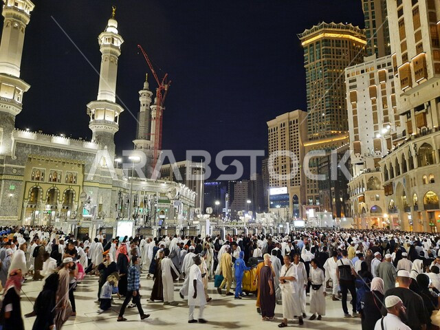 الفن الهندسي المعماري للمباني السكنية المحيطة ببرج الساعة الملكي، تجمع الحجاج والمعتمرين في الساحة الخارجية لمسجد الله الحرام في مكة مكرمة في الليل، مقاصد واماكن لأداء العبادات والتقرب الى الله, معالم دينية اسلامية مقدسة في المملكة العربية السعودية