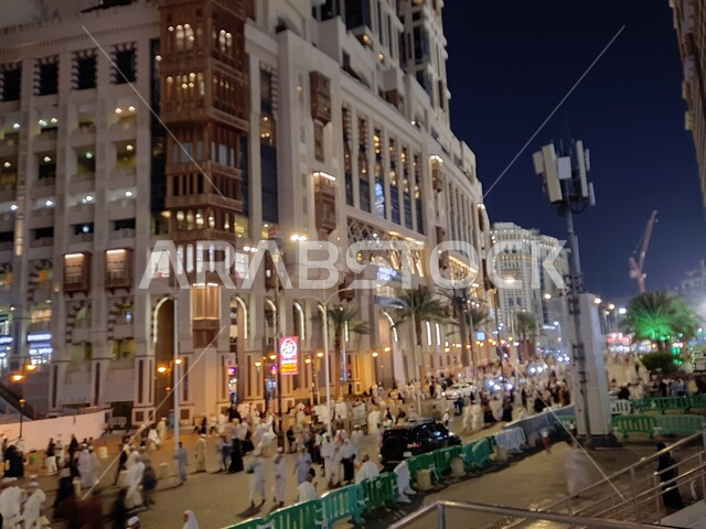 مباني شركة جبل عمر للتطوير العقاري في مكة المكرمة، الفن الهندسي المعماري المتطور للأبراج وناطحات السحاب، فنادق ومنتجعات كونراد الفاخرة المجاورة للمسجد الحرام بالمملكة العربية السعودية، تجمع السياح والحجاج في شارع ابراهيم الخليل في الليل