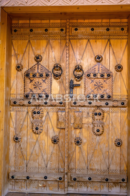 باب خشبي بتصميم معماري عربي قديم، البيوت الأثرية التاريخية في مدينة الرياض، أماكن سياحية تراثية مشهورة في السعودية، الفن الهندسي المعماري للمباني الطينية القديمة في قرية أشيقر في محافظة الشقراء