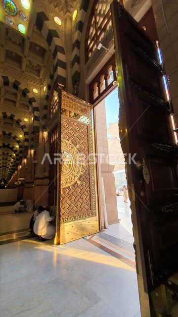 Entrance gate to the Prophet’s Mosque, performing prayers in the Prophet’s Mosque in Medina, worship and getting closer to God, sacred religious landmarks and places in Saudi Arabia, interior decorations and designs in the Islamic style