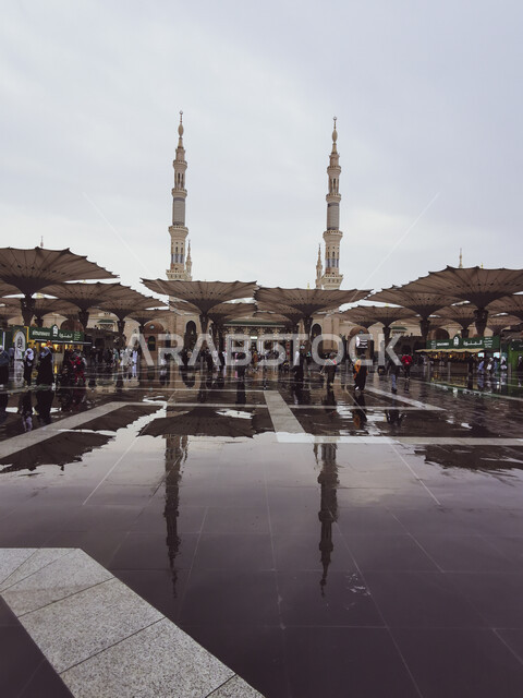 انعكاس المظلات الالكترونية لساحات المسجد النبوي الشريف على مياه المطر، العبادة والتقرب إلى الله، الحجاج المسلمون يمشون أمام الحرم النبوي في المدينه المنوره, أماكن ومعالم دينية مقدسة في السعودية