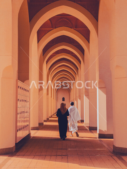 الأقواس والأعمدة بديكورات وتصاميم داخلية على الطراز الاسلامي، زوجان عربيان خليجيان سعوديان يسيران في مسجد بير علي في المدينه المنوره, العبادة والتقرب الى الله، أماكن ومعالم دينية مقدسة في السعودية