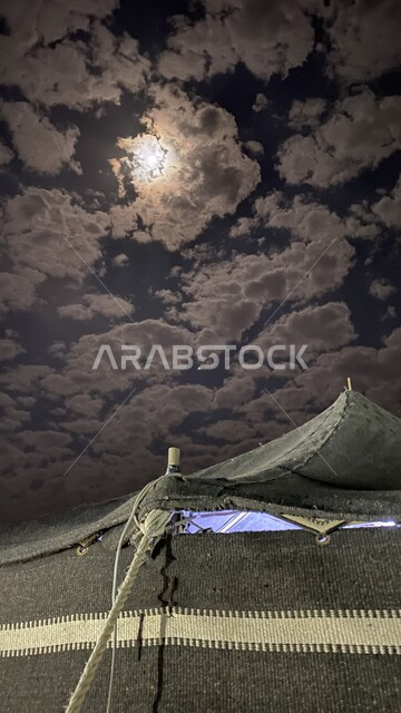 Bait Al Sha’ar tent in the desert of the Kingdom, the quiet atmosphere in the camping places, a traditional popular barn kashta in the desert, traditional Arab gatherings in the prairies, Saudi customs and traditions, the view of the clouds in the sky at night time.