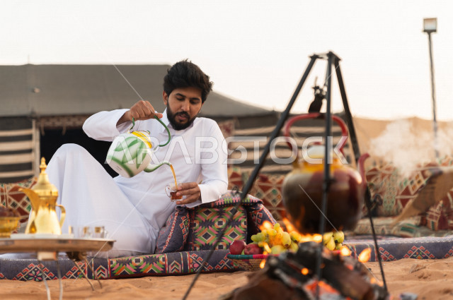 شاب سعودي يشرب الشاي في أجواء صباحية , رجل سعودي يستمتع بأجواء الشتاء في الصحراء 