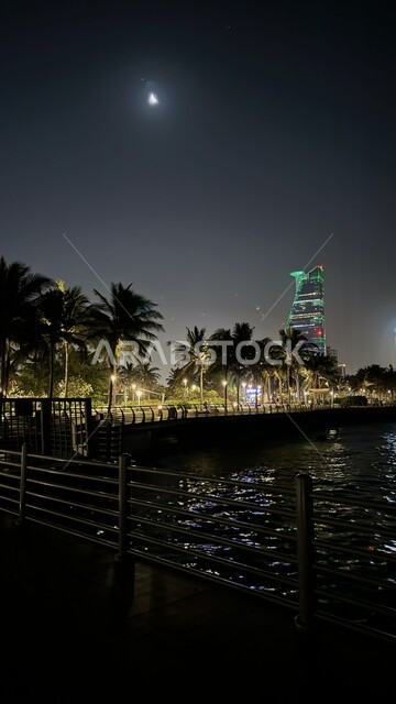 Waterfront in Saudi Arabia, enjoying the water landscape, illuminated towers and skyscrapers in the coastal city, the architectural art of the Corniche Tower building in Jeddah, the skyline and famous commercial landmarks at night