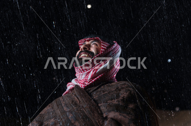 رجل سعودي يستمتع بهطول المطر في صحراء المملكة 