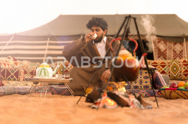 شاب سعودي يشرب الشاي في أجواء صباحية , رجل سعودي يستمتع بأجواء الشتاء في الصحراء 