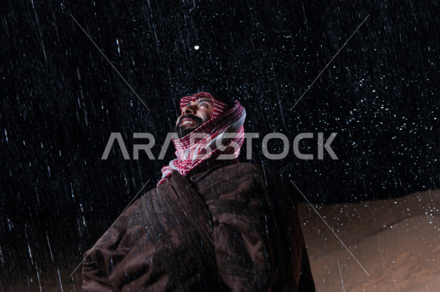 رجل سعودي يستمتع بهطول المطر في صحراء المملكة 