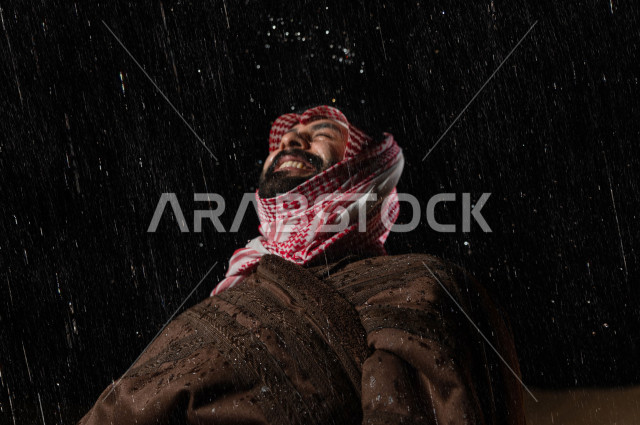 رجل سعودي يستمتع بهطول المطر في صحراء المملكة 