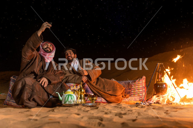 أصدقاء يأخذان صورة سيلفي تذكارية في جلسة برية وأجواء مسائية 