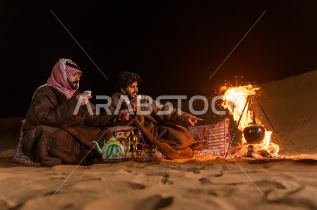 Young Saudis enjoy drinking Arabic coffee in a wild session, an evening adventure for Saudi brothers in the deserts of Saudi Arabia
