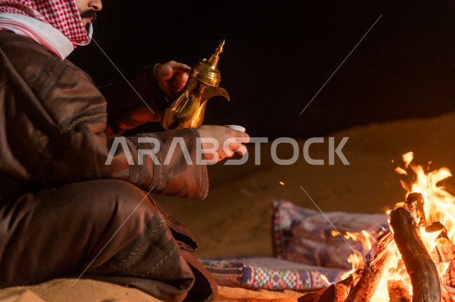 شاب سعودي يصب القهوه العربية في جلسة شعبية , أجواء مسائية في صحراء المملكة 