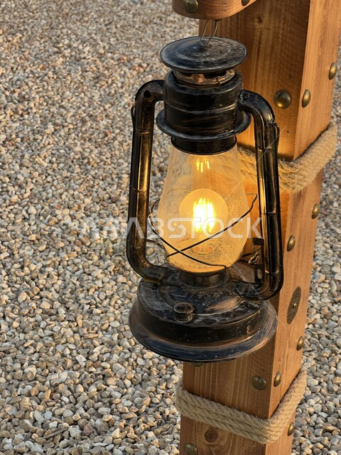  أداوت إنارة بدائية تراثية تقليدية، صورة مقربة لفانوس شعبي عربي سعودي تقليدي, الفوانيس المعدنية المعلقة على الاعمدة الخشبية في منطقة الثمامة في مدينة الرياض