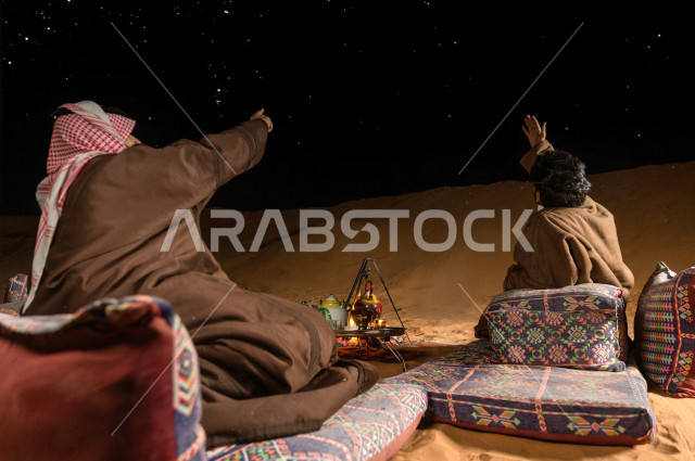 شباب سعوديون في أجواء مسائية يشيران الى السماء في صحراء المملكة , شباب سعوديون يتحدثون وينظرون  الى السماء في أجواء هادئة في صحاري المملكة العربية السعودية 