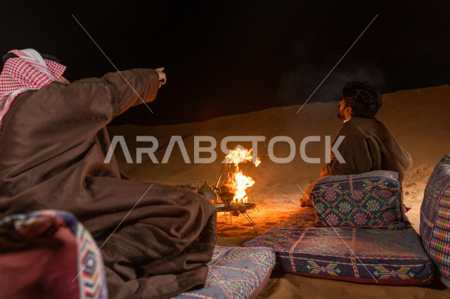 Young Saudis in the evening atmosphere pointing to the sky in the Kingdom's desert, Young Saudis talk and look a the sky in a calm atmosphere in the deserts of Saudi Arabia