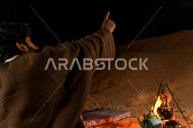 شباب سعوديون في أجواء مسائية يشيران الى السماء في صحراء المملكة , شباب سعوديون  يتحدثون وينظرون  الى السماء في أجواء هادئة في صحاري المملكة العربية السعودية 