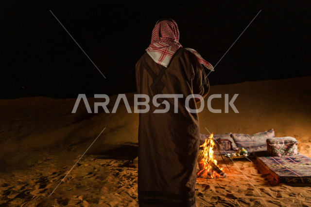 شاب سعودي يقف عند جلسة بر  في صحراء المملكة العربية السعودية  , رحلة تخيم لرجل سعودي  في صحاري المملكة 