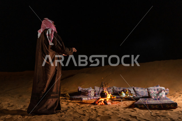 شاب سعودي يقف عند جلسة بر  في صحراء المملكة العربية السعودية  , رحلة تخيم لرجل سعودي  في صحاري المملكة 