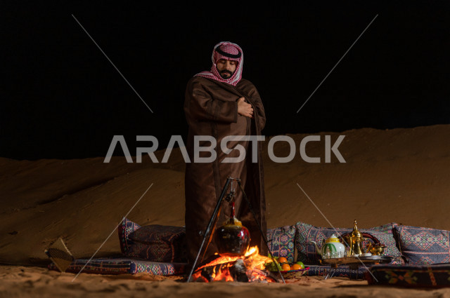 شاب سعودي يقف عند جلسة بر  في صحراء المملكة العربية السعودية  , رحلة تخيم لرجل سعودي  في صحاري المملكة 