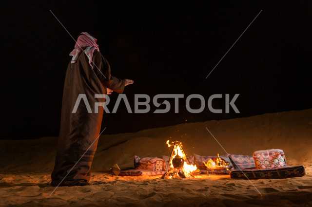 شاب سعودي يقف عند جلسة بر  في صحراء المملكة العربية السعودية  , رحلة تخيم لرجل سعودي  في صحاري المملكة 