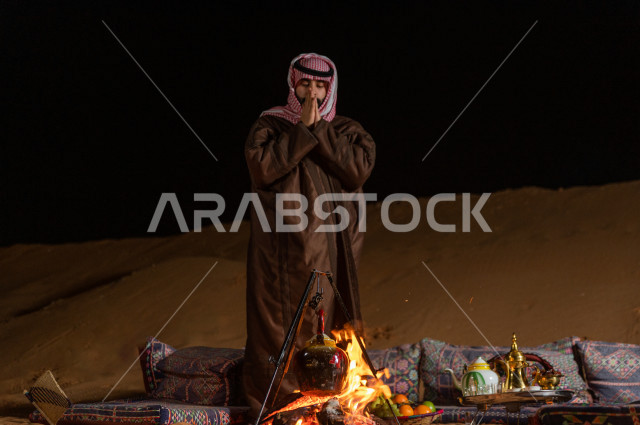 شاب سعودي يقف عند جلسة بر  في صحراء المملكة العربية السعودية  , رحلة تخيم لرجل سعودي  في صحاري المملكة 