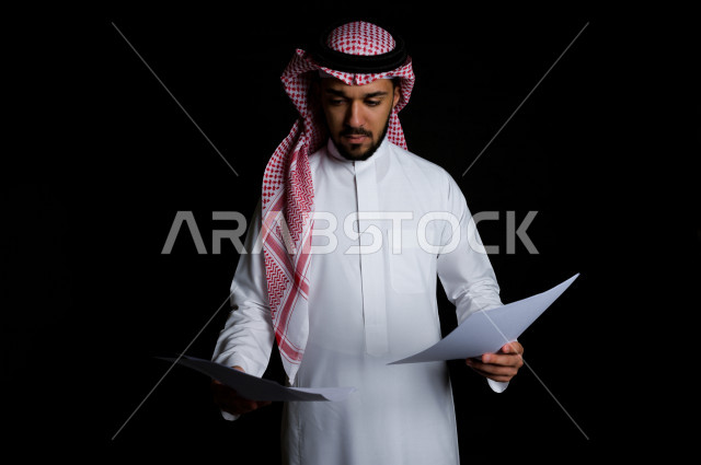 بورتريه لرجل سعودي خليجي سعيد بإيماءات الوجه المختلفة ، تعابير وجه و يدين مختلفة , يمسك بيده لوحة بيضاء ، خلفية سوداء